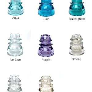 May include: A collection of eight glass electrical insulators arranged in a grid, featuring various colors including aqua, blue, bluish-green, ice blue, purple, smoke, clear, and wheat, each with embossed text and a tiered, rounded shape.