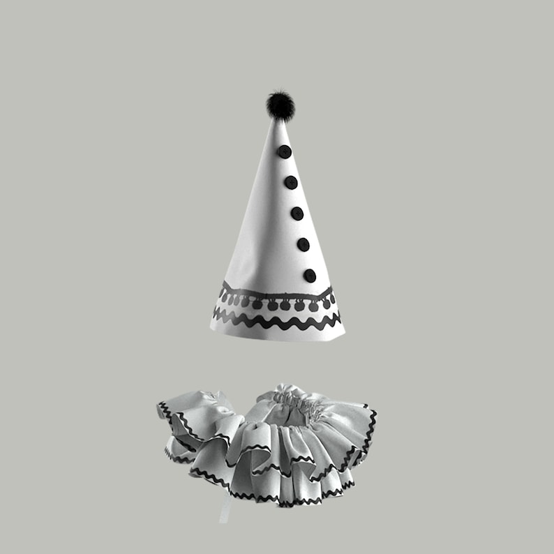 May include: A white and black clown costume with a pointed hat and a ruffled collar.