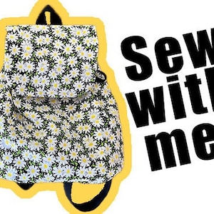 May include: A small black backpack with a white daisy print. The backpack has a drawstring closure and adjustable straps. The text "Sew with me!" is written in black letters on a white background.