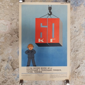 Puede incluir: Cartel de seguridad soviético vintage con un trabajador y un bloque rojo suspendido por un gancho de grúa. El bloque muestra el número "60" y las letras "KG". El cartel tiene texto en ruso en la parte inferior y un fondo azul claro.