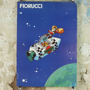 Könnte beinhalten: Vintage FIORUCCI-Poster mit einem Cartoon-Weihnachtsmann in einer Rakete vor blauem Weltraumhintergrund. Die Rakete hat ein Schachbrettmuster und das FIORUCCI-Logo. Ein grüner Planet ist unten rechts sichtbar.