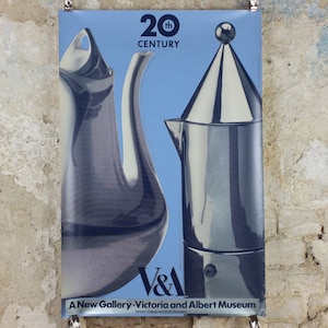 Pode incluir: Cartaz com dois objetos metálicos estilizados sobre um fundo azul claro. O cartaz tem a etiqueta "20th Century" e inclui o logótipo V&A e o texto "A New Gallery - Victoria and Albert Museum."
