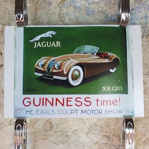 May include: Vintage Jaguar XK120 advertisement. The poster features a brown convertible car with white-walled tires against a green background. The Jaguar logo and the text "GUINNESS time!" are also visible.