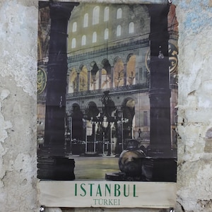 May include: A vintage poster featuring a nighttime view of a building in Istanbul, Turkey. The poster has a faded appearance and is framed by two dark columns. The text "ISTANBUL TURKEI" is printed at the bottom in green.