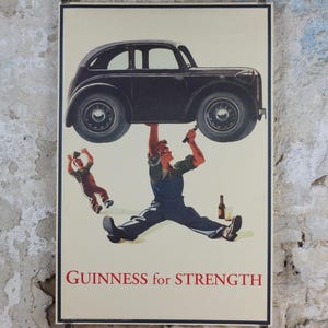 May include: Vintage Guinness advertisement poster. The poster features a man lifting a black car above his head with the text "Guinness for Strength" in red. Another man is falling in the background. A bottle of Guinness is on the ground.