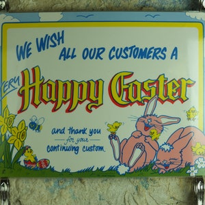 Könnte beinhalten: Rechteckiges Schild mit hellblauem Rand und den Worten "WE WISH ALL OUR CUSTOMERS A VERY Happy Easter" in roter und gelber Schrift. Das Schild zeigt Cartoon-Hasen, Küken und Blumen.