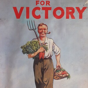 Puede incluir: Cartel vintage con el texto "DIG ON FOR VICTORY" en rojo. Un granjero sonriente con una pipa lleva una horca, zanahorias y una cesta de verduras. El fondo muestra una carretera y peque&ntilde;os edificios.
