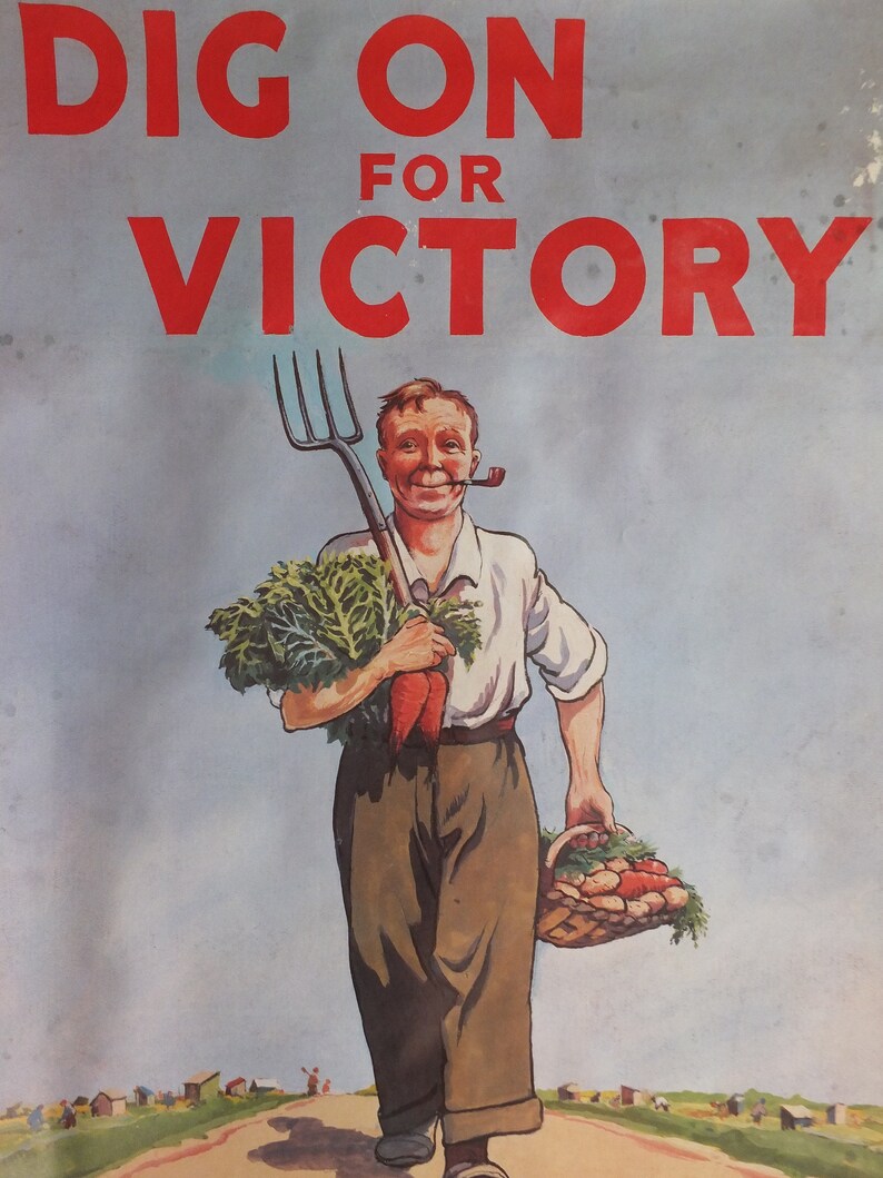 Puede incluir: Cartel vintage con el texto "DIG ON FOR VICTORY" en rojo. Un granjero sonriente con una pipa lleva una horca, zanahorias y una cesta de verduras. El fondo muestra una carretera y peque&ntilde;os edificios.