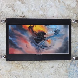 May include: A fantasy art print depicting a battle scene with a dragon and a warrior. The artwork features a fiery sky and a dramatic clash of light and shadow. The print is held in place by four metal clips.