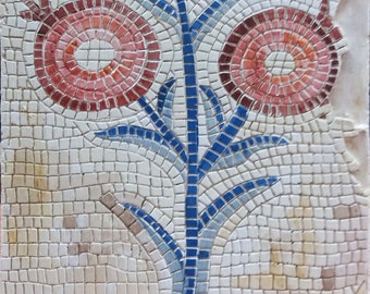 May include: A mosaic tile depicting a stylized plant with two red flowers. The plant has blue and white leaves and a blue stem. The flowers are made up of concentric circles of red, pink, and white tiles.