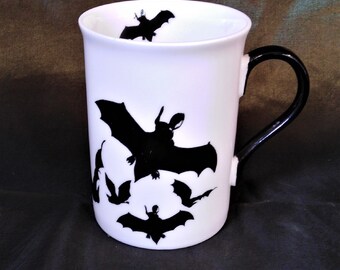 Halloween bat mug made of pure white bone china covered with hand decoration of black flying bats and with a black painted handle.
