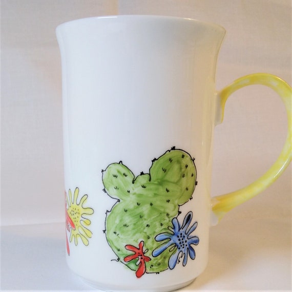 Cactus and desert flowers and a yellow handle on a mug.