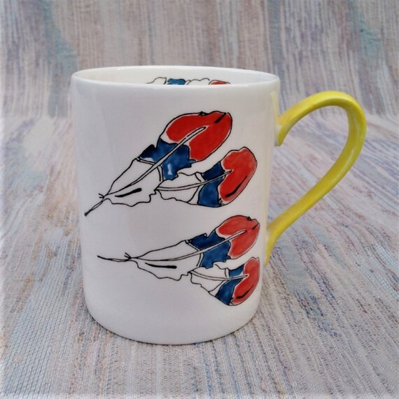 Mug decorated with red, white and blue feathers.