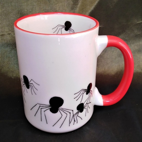 Halloween - Spiders creeping around a large half pint china mug with a red handle and rim and with a spider inside the rim.