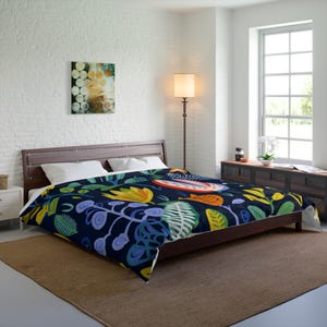 May include: A dark blue duvet cover with a colorful floral pattern featuring yellow, green, blue, and red accents. The duvet cover is on a bed with white pillows and a wooden headboard.