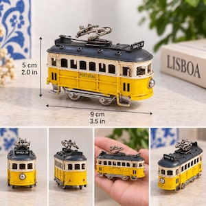May include: A miniature yellow and dark gray tram model with the text PORTUGAL and GRA&Ccedil;A 28. The model measures 2.0 inches in height and 3.5 inches in length, featuring a roof-mounted pantograph, multiple windows, and small wheels on a metal frame.