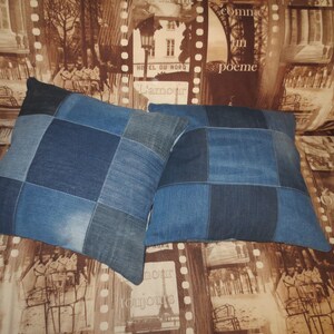 Könnte beinhalten: Zwei blaue Denim-Patchwork-Kissen mit quadratischem Muster. Die Kissen liegen auf einem braunen Sofa mit einem gemusterten Stoff, der Bilder von Pariser Straßen und Gebäuden zeigt.