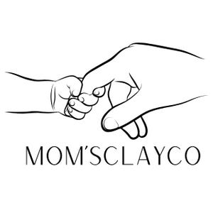 May include: Black and white line drawing of an adult hand holding a baby's hand. The baby's hand is grasping the adult's index finger. The text "MOM'SCLAYCO" is below the hands.