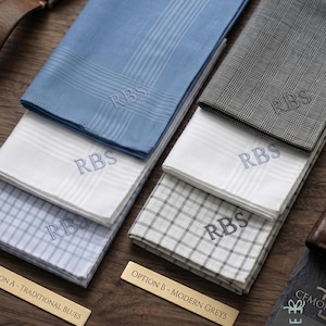 May include: A collection of personalized handkerchiefs in various colors and patterns, including blue, white, and gray. Each handkerchief is embroidered with the initials "RBS". The image includes two small gold-colored signs that read "OPTION A - TRADITIONAL BLUES" and "OPTION B - MODERN GREYS".