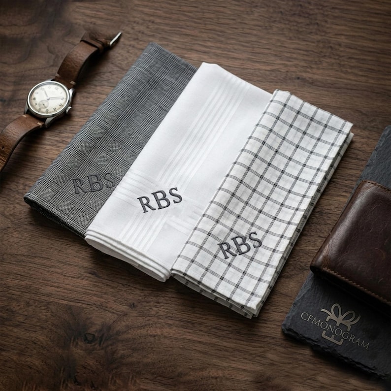 Puede incluir: Tres pa&ntilde;uelos personalizados con las iniciales "RBS" bordadas. Uno es a cuadros grises, otro blanco con rayas y el otro blanco con un patr&oacute;n de cuadr&iacute;cula negra. Tambi&eacute;n hay un reloj y una cartera de cuero marr&oacute;n.