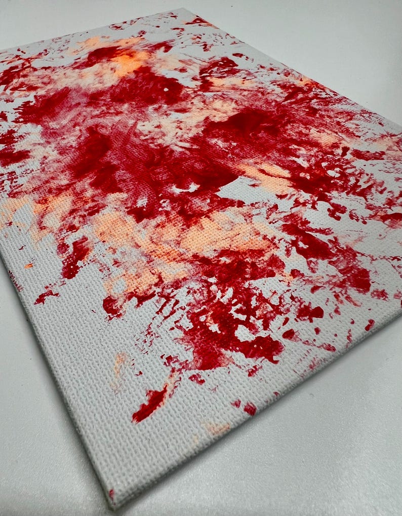 May include: Abstract painting on canvas with red and orange paint splatters on a white background.