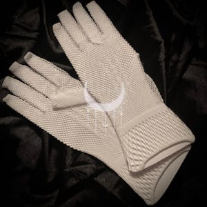 May include: A pair of white mesh fingerless gloves. The gloves are made of a fine, delicate mesh fabric and have a diamond pattern.