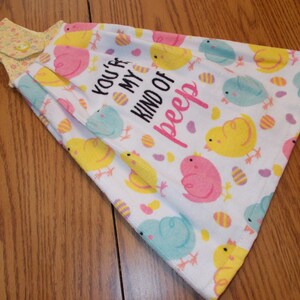 May include: A white kitchen towel with a yellow, pink, and blue chick design and the text "You're my kind of peep".