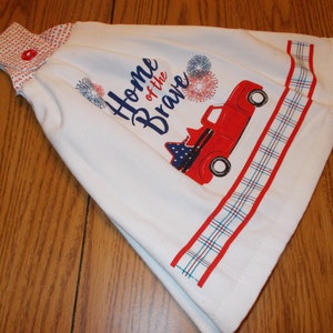 May include: White kitchen towel with a red truck, fireworks, and the text "Home of the Brave".