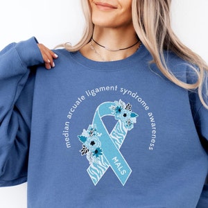 May include: A blue sweatshirt with a light blue ribbon with a floral design and the text "median arcuate ligament syndrome awareness" and "MALS".