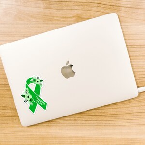Pu&ograve; includere: Un nastro verde con fiori bianchi e il testo "Cerebral Palsy" su un laptop bianco.