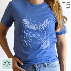 May include: A blue t-shirt with a white outline of the human digestive system with flowers inside. The text "heather true royal" is printed on the shirt.
