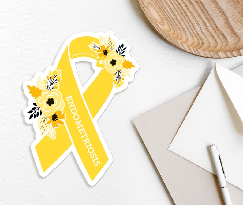 May include: Yellow ribbon with a floral design and the word "ENDOMETRIOSIS" printed on it.