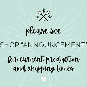 May include: A light blue background with white rays emanating from the center. The text "please see SHOP "ANNOUNCEMENT" for current production and shipping times" is written in black cursive font. A small heart is at the bottom of the image.