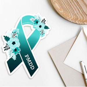 May include: Teal blue awareness ribbon with a floral design and the text "PMDD" on a white background.
