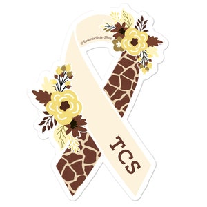 May include: A white ribbon with a brown and tan giraffe print, tied in a bow with a floral design. The ribbon has the text "TCS" on it.