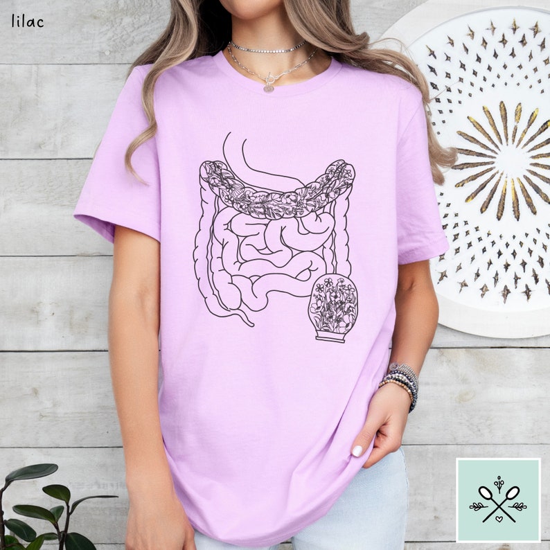 May include: A lilac t-shirt with a black line drawing of the human digestive system with flowers inside the small intestine.