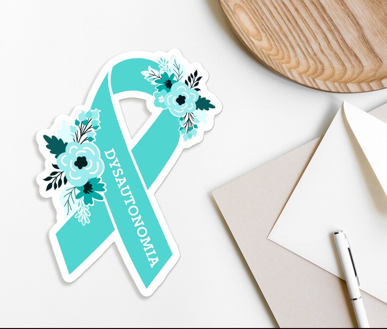 Op de afbeelding: Turquoise blauwe lint met een bloemenontwerp en het woord "DYSAUTONOMIA" erop.