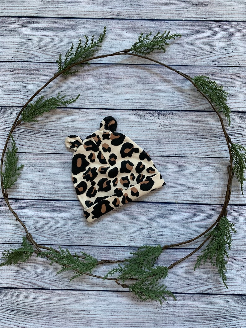 May include: A beige and brown leopard print baby hat with ear flaps.