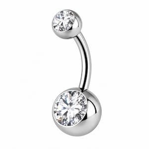 May include: A curved barbell belly button ring made of polished silver-toned metal. The jewelry features a smaller round clear gemstone at the top and a larger round clear gemstone set into a spherical base at the bottom.