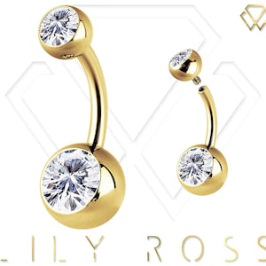 Può includere: Anello per ombelico dorato con due pietre rotonde trasparenti. L'anello è in acciaio chirurgico ed è disponibile in diverse misure.