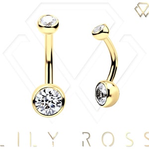 Puede incluir: Anillo de ombligo dorado con piedras redondas transparentes. El anillo es curvo y tiene una pequeña bola en la parte superior.