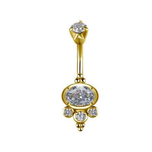 May include: Gold belly button ring with a large oval-shaped clear gemstone and smaller clear gemstones on the sides.