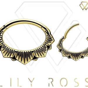 May include: Gold-toned body jewelry with a decorative, scalloped edge. The jewelry is in the shape of a hoop.