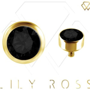 May include: Gold-toned body jewelry with a black gem top. The gem is round and has a faceted design. The jewelry is designed for a dermal piercing.