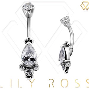 May include: A silver belly button ring with a teardrop-shaped clear crystal and smaller clear crystals around it.