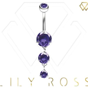 Puede incluir: Un piercing de ombligo plateado con una cadena colgante de tres piedras preciosas púrpuras.