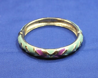 May include: A gold bangle bracelet with a light blue and purple enamel design. The bracelet has a geometric pattern.