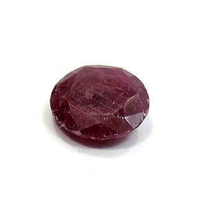 Peut inclure: Une pierre précieuse de rubis rouge foncé avec une taille facetée. La pierre précieuse est de forme ovale et a une finition brillante et polie.