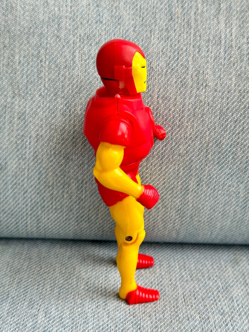 Może przedstawiać: Plastikowa figurka Iron Mana w kolorze czerwonym i ż&oacute;łtym. Figurka stoi z rękami wzdłuż bok&oacute;w i głową zwr&oacute;coną w prawo. Figurka jest w dynamicznej pozie.