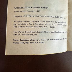 Pode incluir: Um close-up de uma p&aacute;gina de livro com texto de uma edi&ccedil;&atilde;o da Warner Paperback Library. O texto inclui as informa&ccedil;&otilde;es de direitos autorais de 1973, a data da primeira impress&atilde;o de fevereiro de 1973 e o endere&ccedil;o da editora em Nova York.